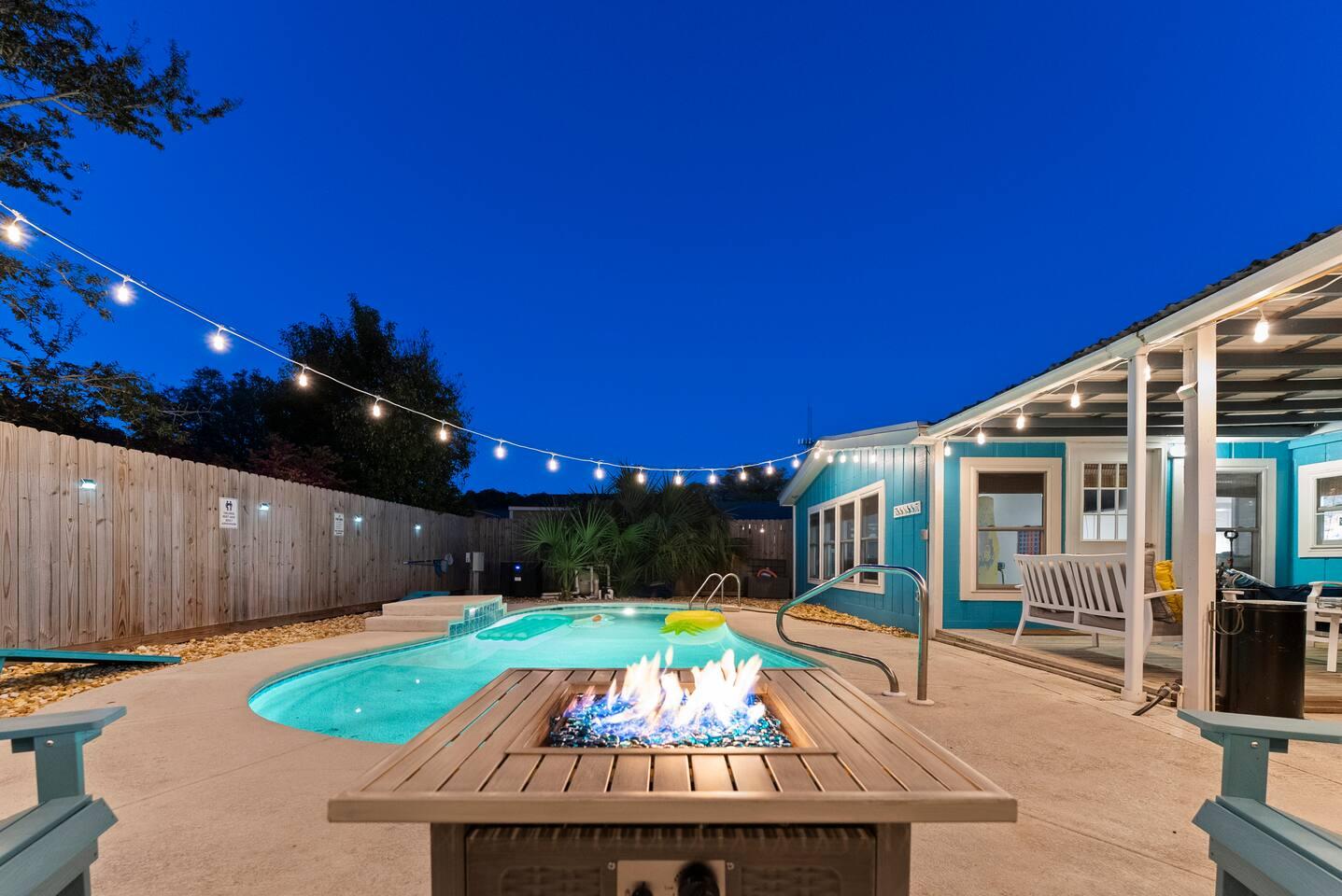 Backyard oasis with string lights, pool, and fire pit